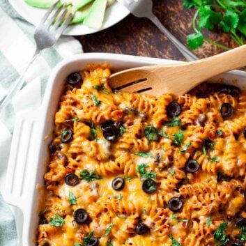 Mexican pasta bake in a casserole dish with a serving spoon.