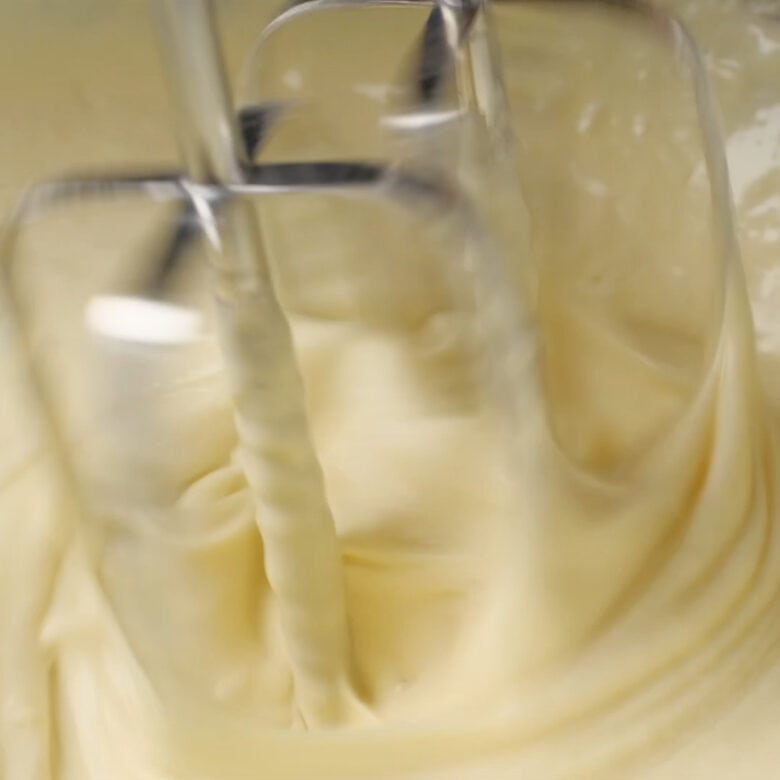 Popovers batter being blended with a hand mixer.