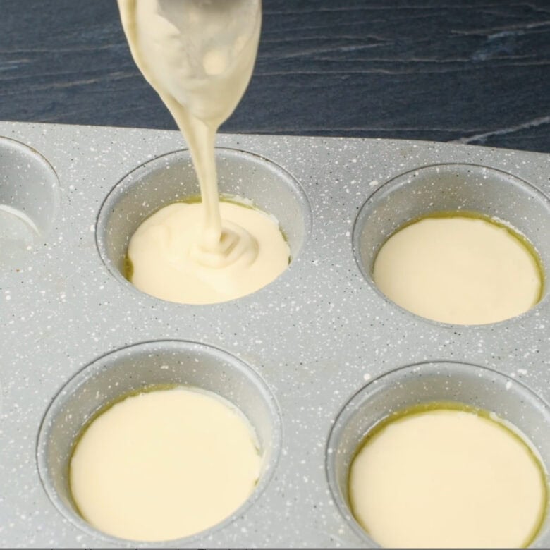 Popover tins being filled halfway with batter.