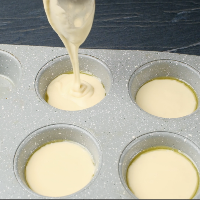 Popover tins being filled halfway with batter.