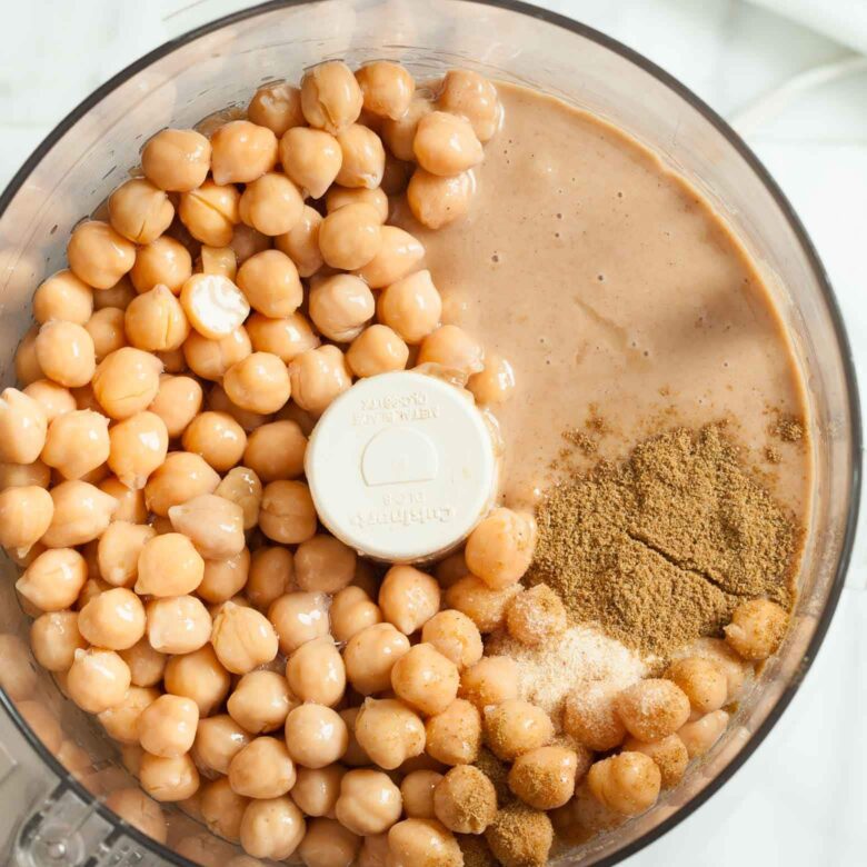 Overhead shot of a food processor with ingredients to make hummus.