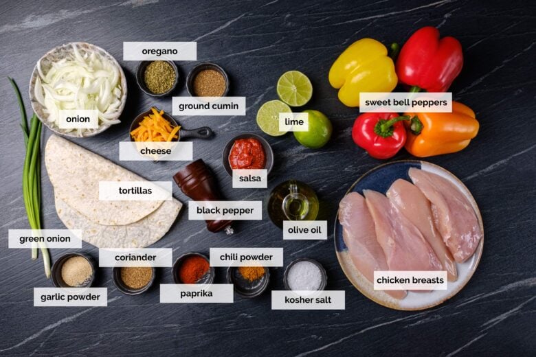 Overhead shot of sheet pan chicken fajita ingredients on a black countertop.