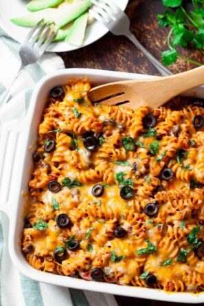 Mexican pasta bake in a casserole dish with a serving spoon.