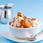 A bowl of Bananas Foster ice cream with a spoon on the side.