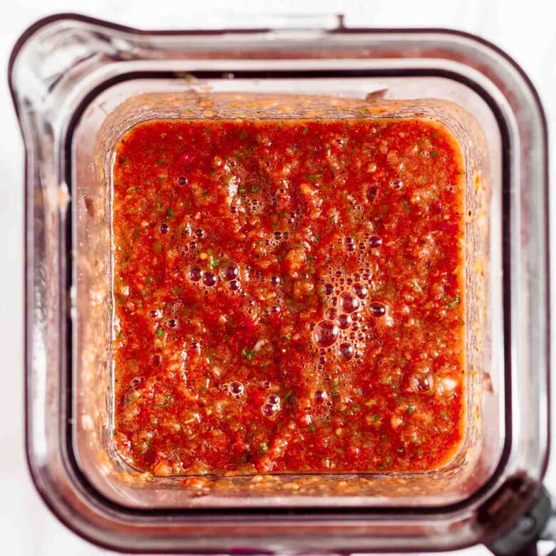 A blender filled with freshly made blender salsa.