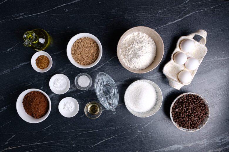 Healthy chocolate cake ingredients such as flour, cocoa, flax, sugar, eggs, olive oil, vanilla extract.