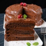 A slice of eggless chocolate cake on a plate with a fork.