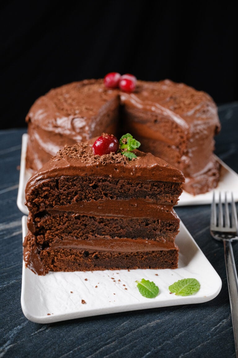 A slice of eggless chocolate cake on a plate with a fork.