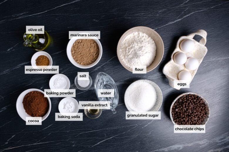 Ingredients for a healthy chocolate cake on a black table.