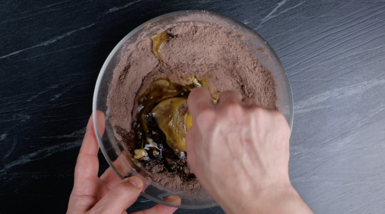 Mixing dry ingredients with wet ingredients in a bowl to make healthy chocolate cake.