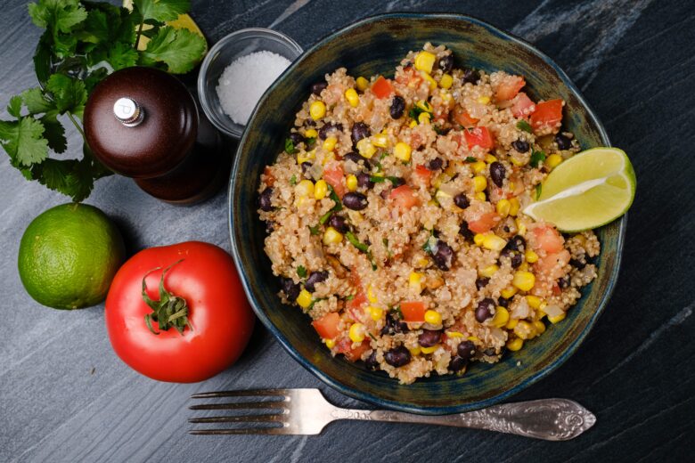 Overhead shot of Mexican quinoa in a bowl with a lime wedge and a fork on the side.