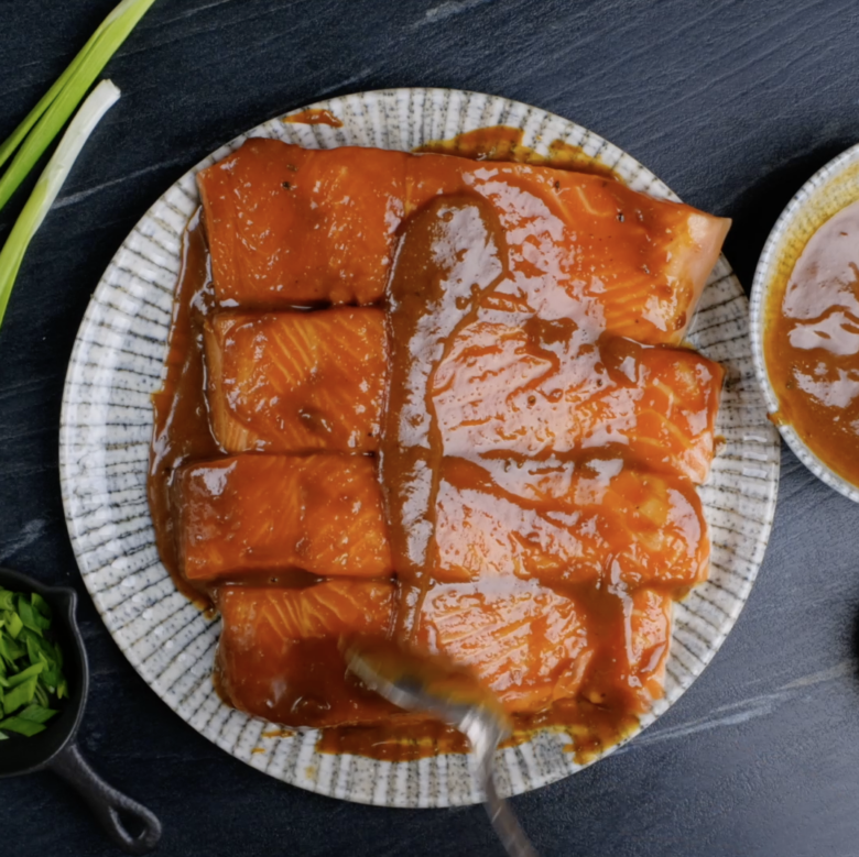 Salmon fillets covered in miso glaze on a plate.