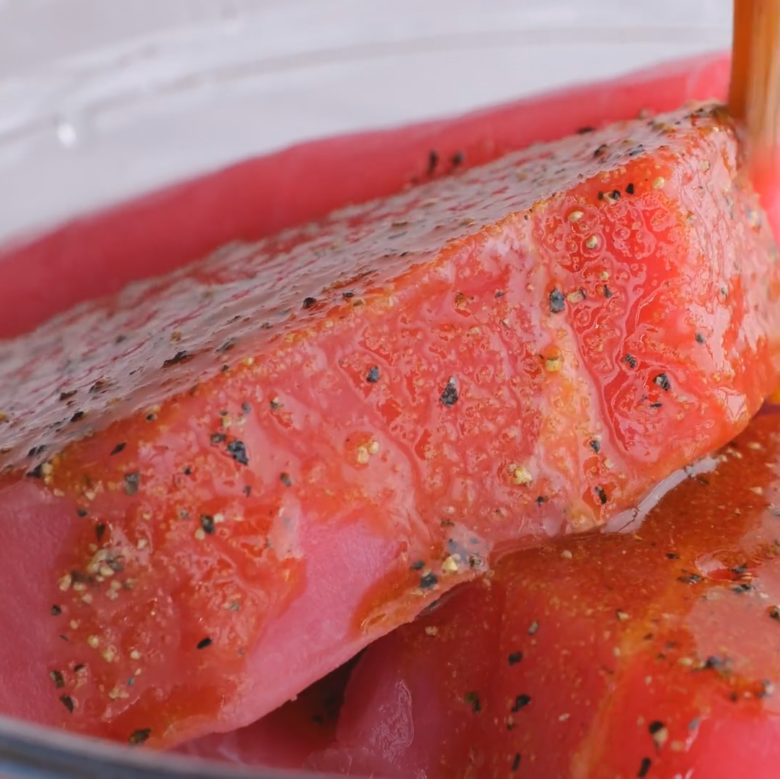 Raw ahi tuna steaks being prepared for searing.