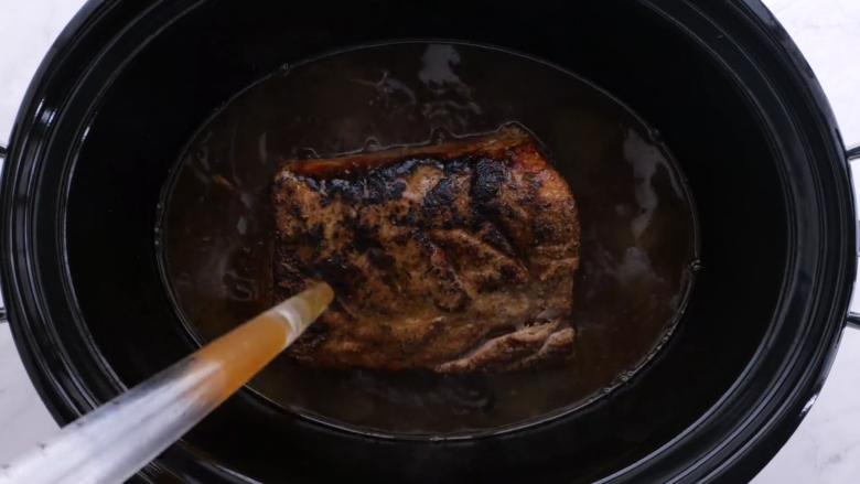 slow cooker pork loin being basted.