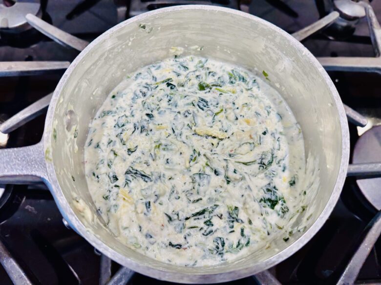 Spinach artichoke dip mixture in a pot on the stove.