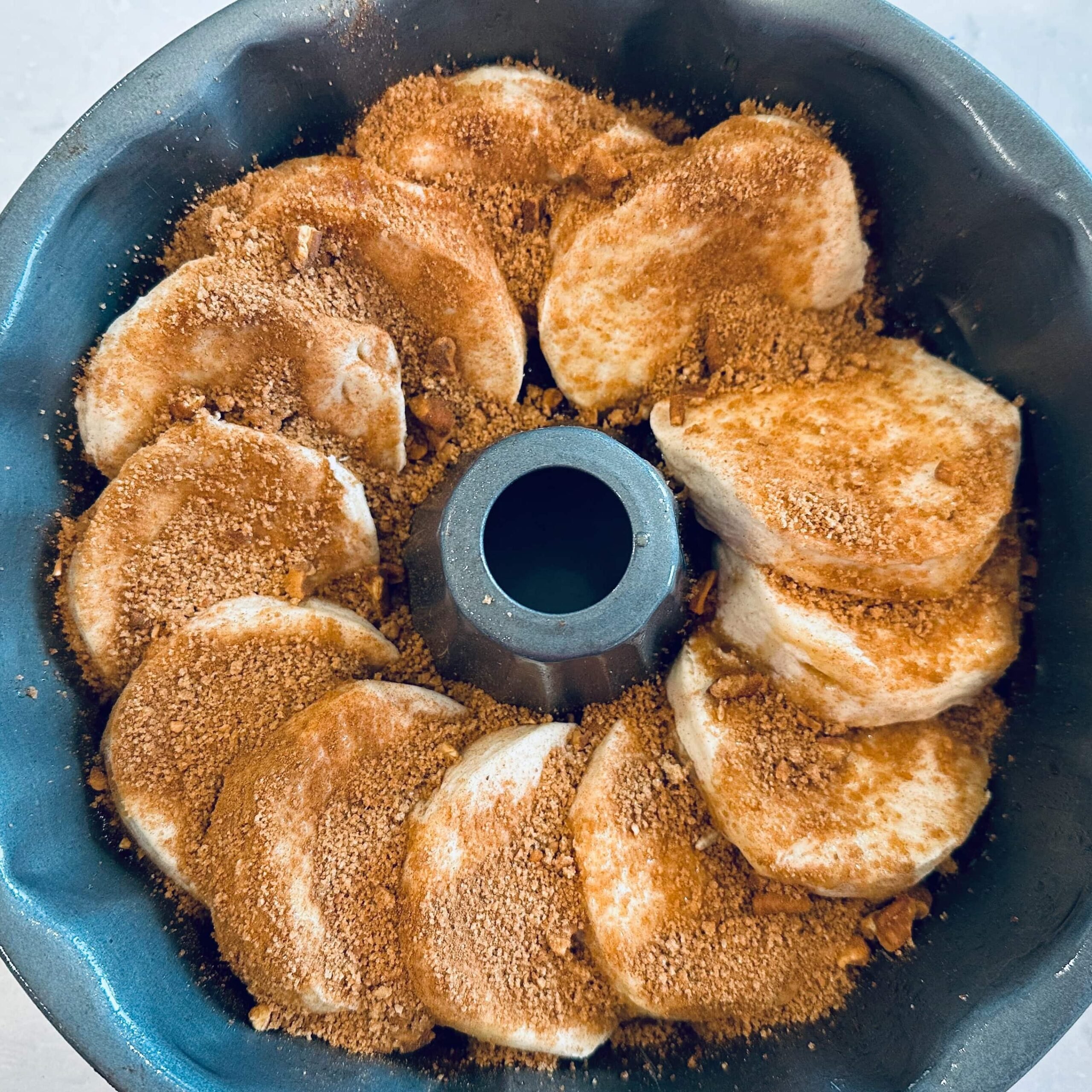 Overlapping biscuits in a bundt pan covered with cinnamon and brown sugar to make sticky buns.
