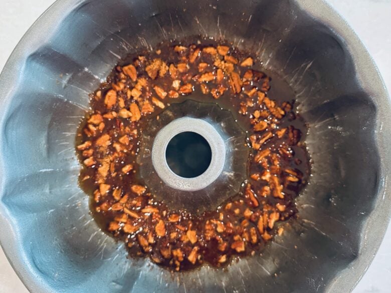 Syrup mixture with nuts in a greased bundt pan to make sticky buns.