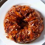 Overhead shot of aasy stick buns with caramel-like sauce and pecans on a plate.