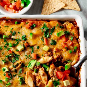 Taco Pasta with tortilla chips and salsa in a casserole dish.