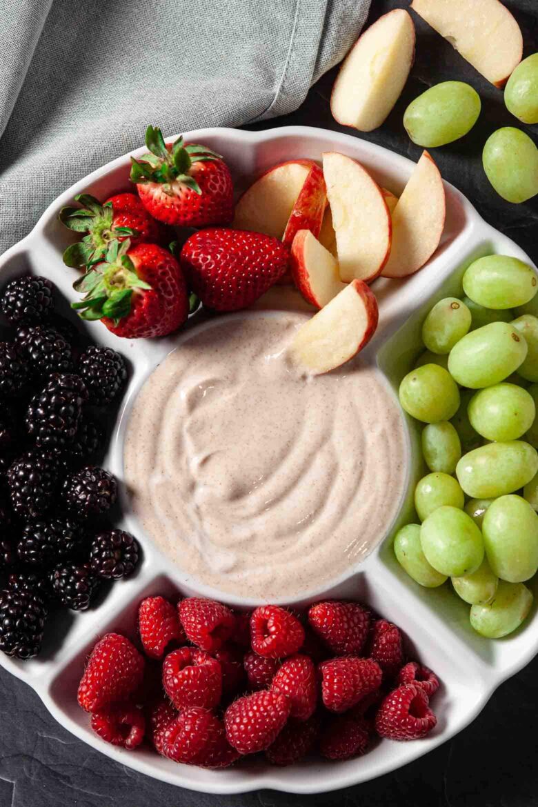 A plate of fruit dip with berries and grapes.
