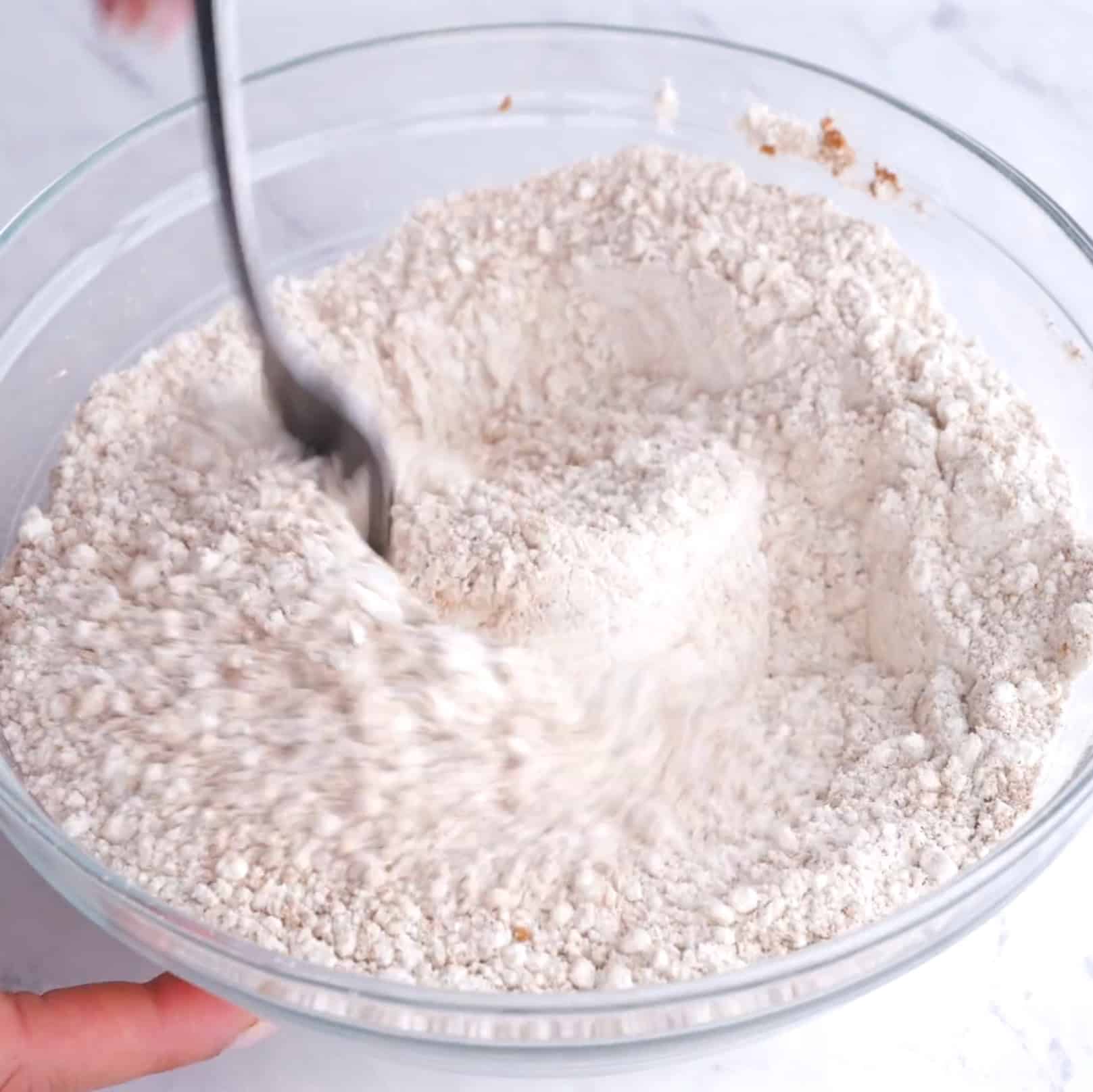 Dry ingredients to make carrot cake being mixed in a glass bowl.