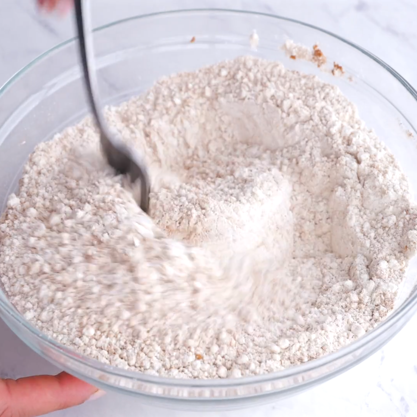 Dry ingredients to make carrot cake being mixed in a glass bowl.