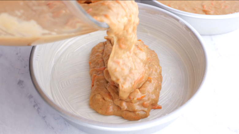 Carrot cake batter being poured into a cake pan.