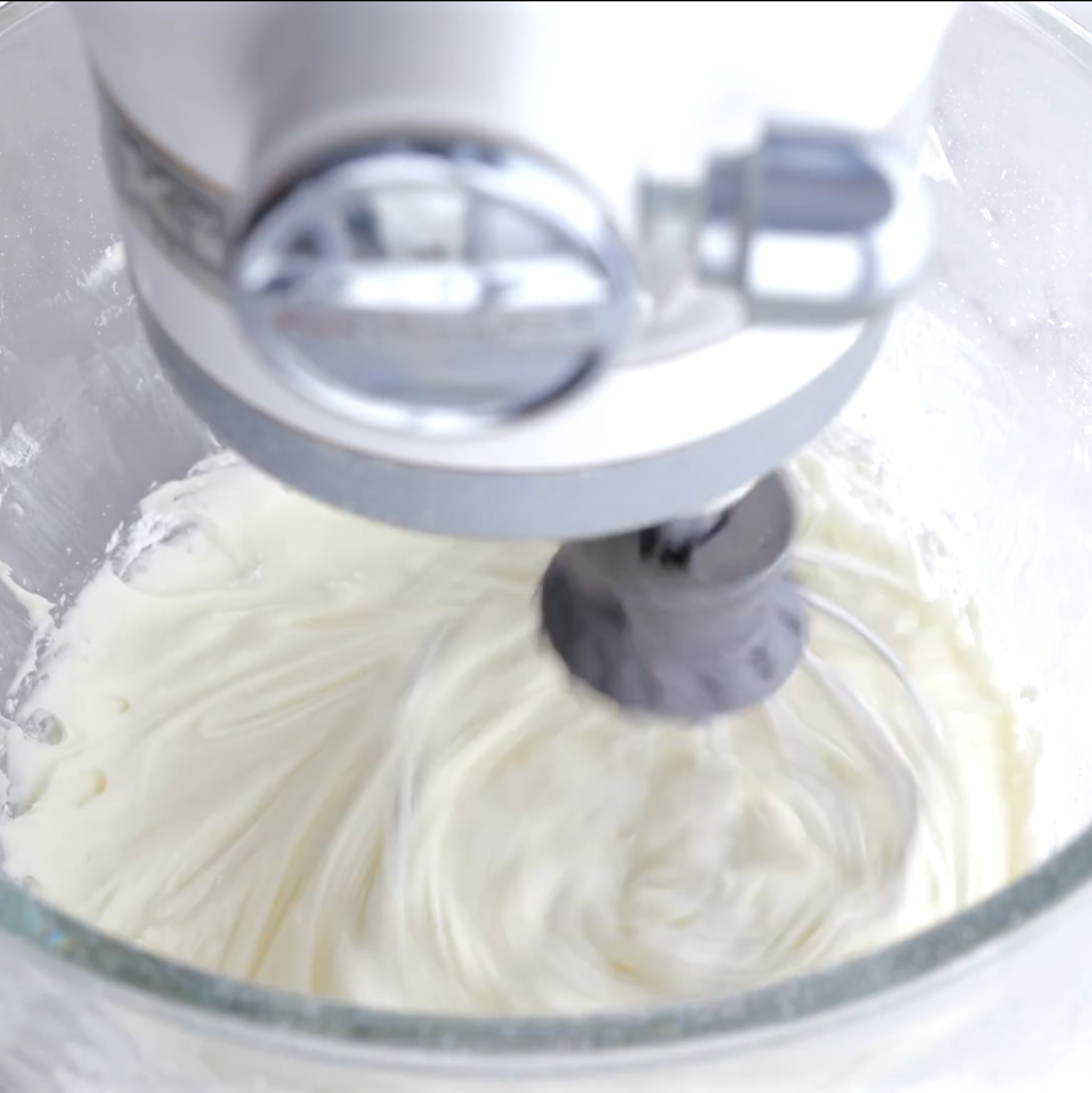 Cream cheese frosting being whisked in a bowl of a stand mixer.