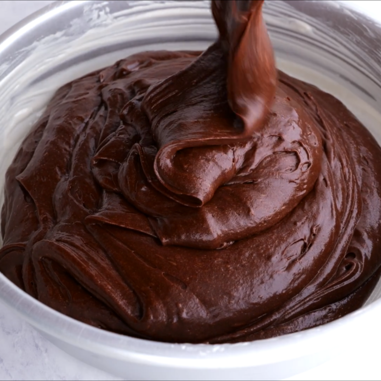 Chocolate strawberry cake batter being poured into a cake pan.