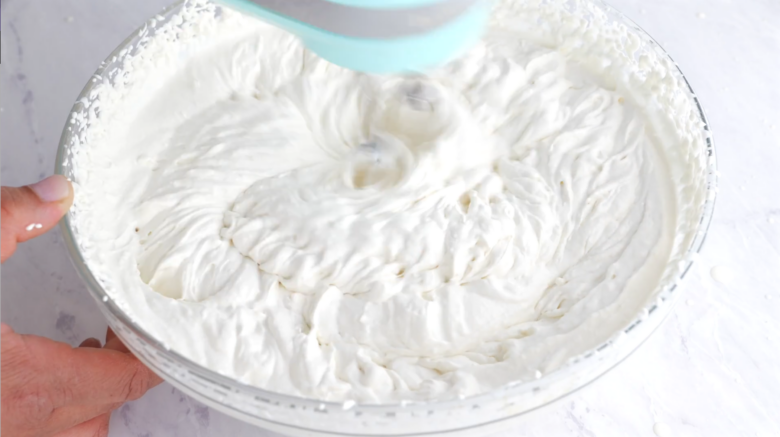 Whipped cream being beaten to form stiff peaks.
