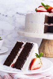 A slice of chocolate strawberry cake with sliced strawberry on a white plate.