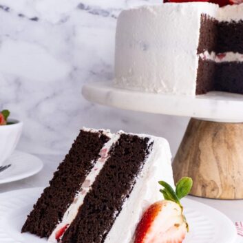A slice of chocolate strawberry cake with sliced strawberry on a white plate.
