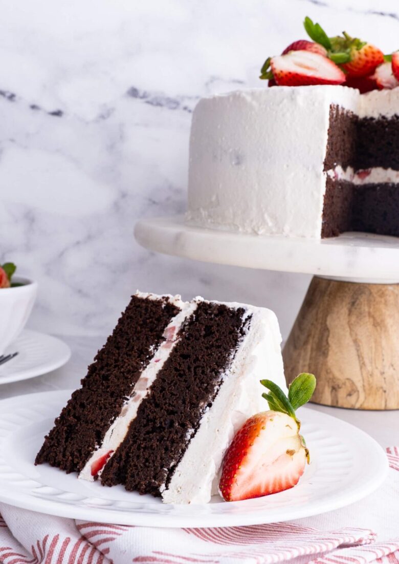 A slice of chocolate strawberry cake with sliced strawberry on a white plate.