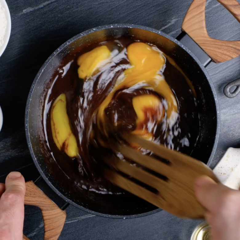 Eggs being whisked into chocolate-butter mixture to make dark chocolate brownies.