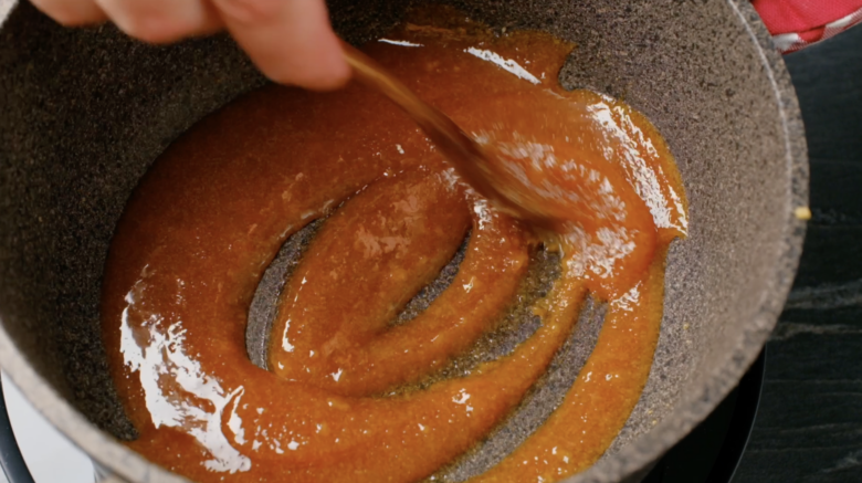 Sugar being heated and whisked in a pan to make salted caramel sauce.