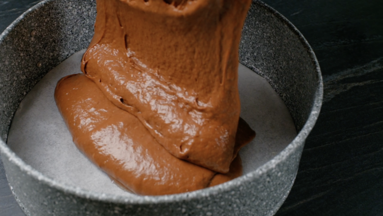 chocolate cake batter being poured into pan.