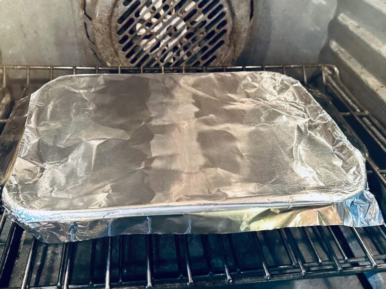 Eggs benedict casserole covered with foil in the oven.