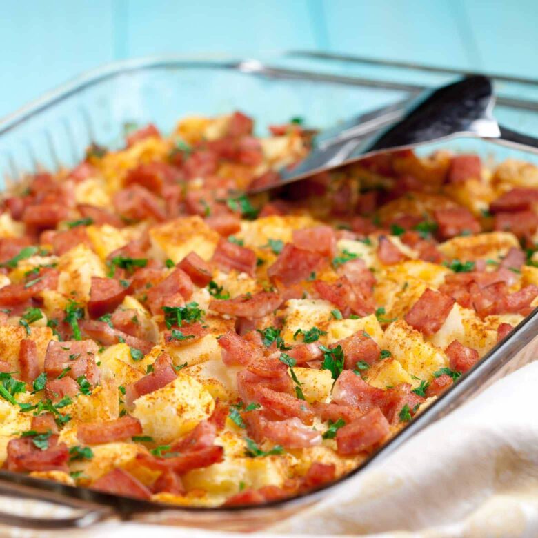 Closeup shot of eggs benedict casserole with chopped Canadian bacon, English muffins, and savory eggs.