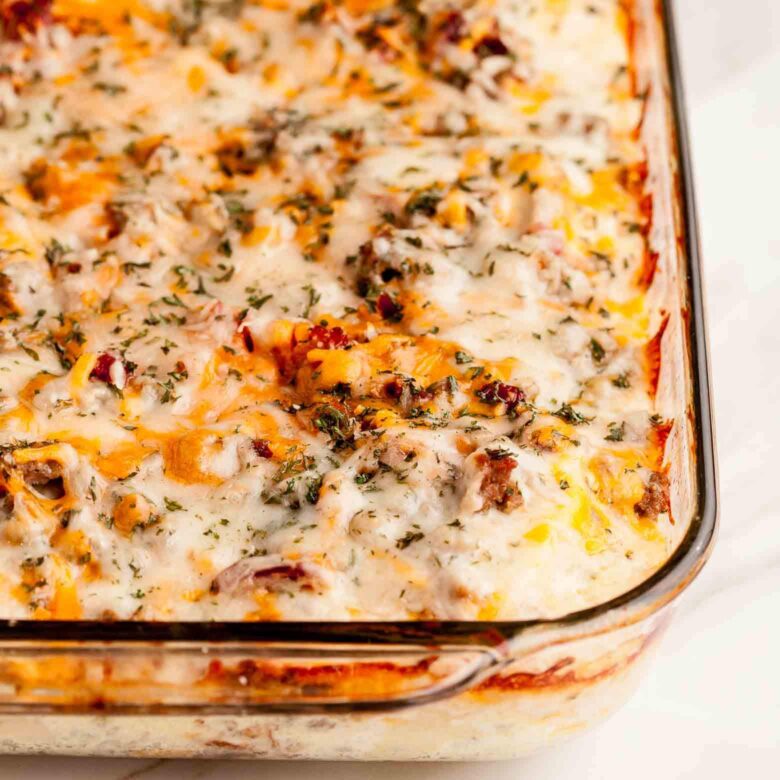 Closeup shot of a freshly-baked English Muffin Breakfast casserole with melted cheese and herbs in a glass dish.