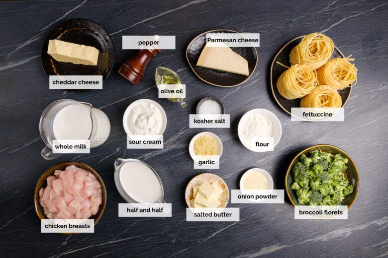 Overhead shot of ingredients to make chicken fettuccini Alfredo on a dark surface.