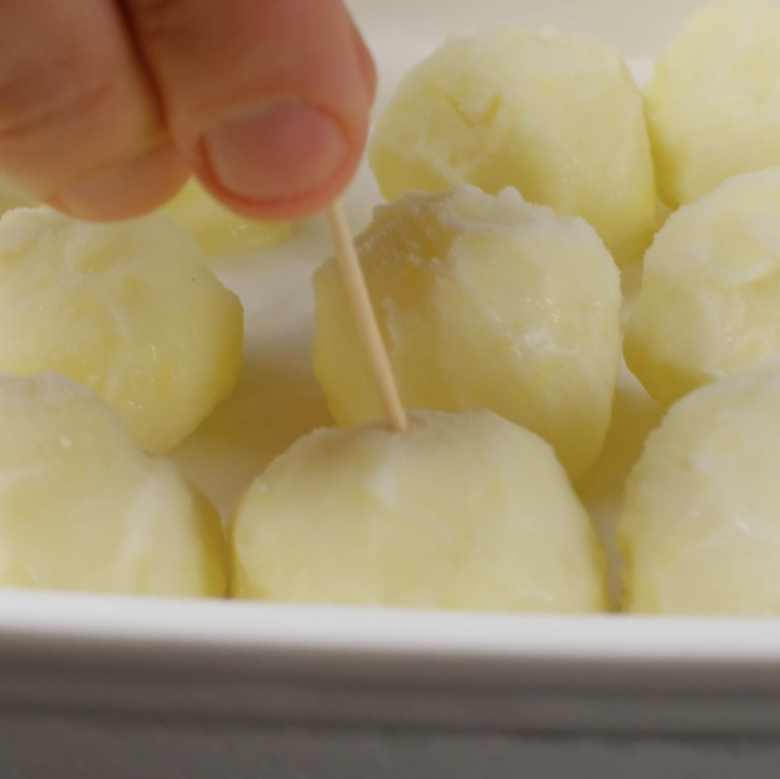 A toothpick being inserted in ice cream balls.