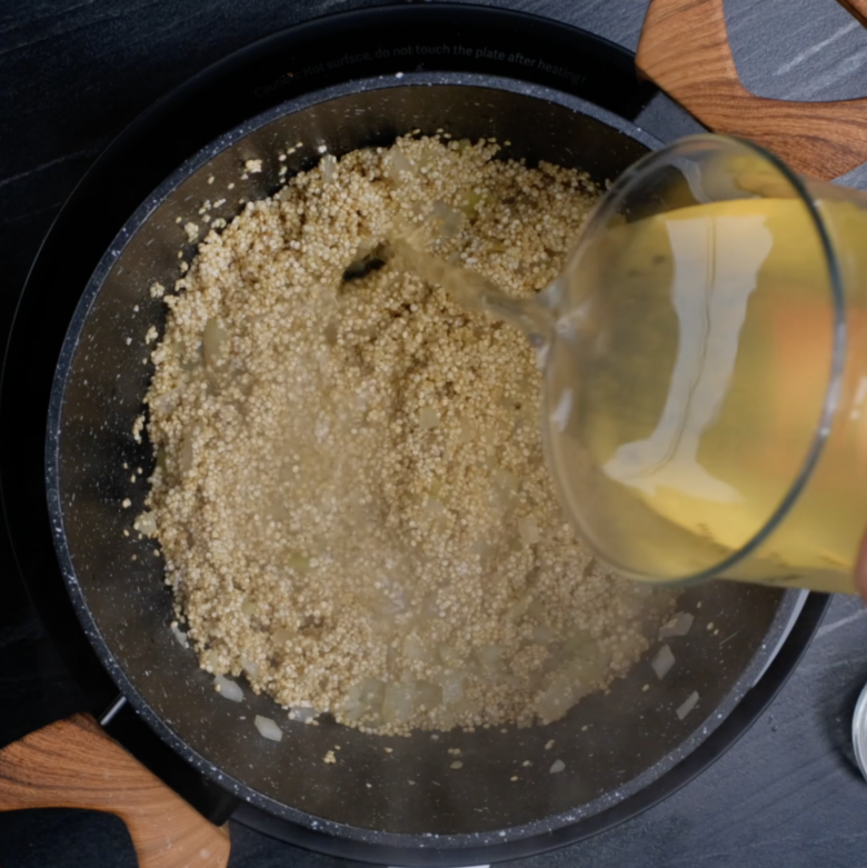 Broth being poured into a pot with quinoa to make Mexican quinoa.