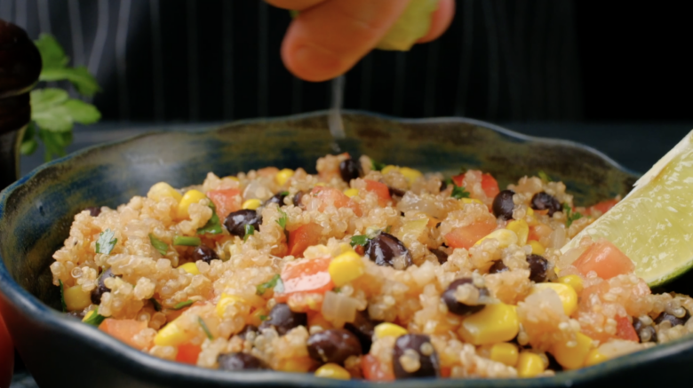 Fresh lime juice being squeezed over Mexican quinoa before serving.