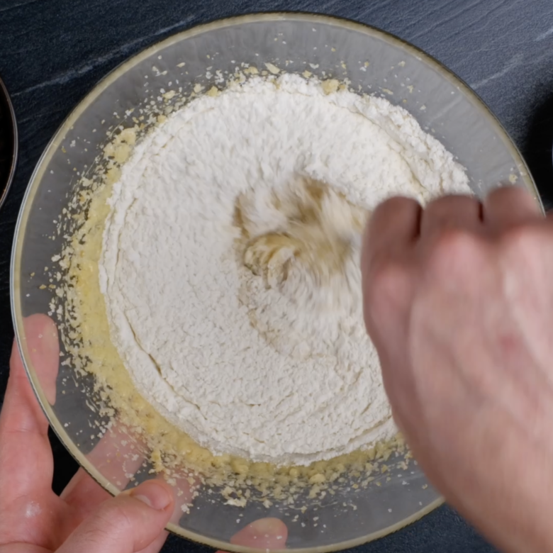 Flour being mixed into butter mixture to make s'mores cookie bars.