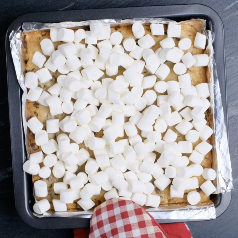A s'mores cookie bar pan with marshmallows on top of it.