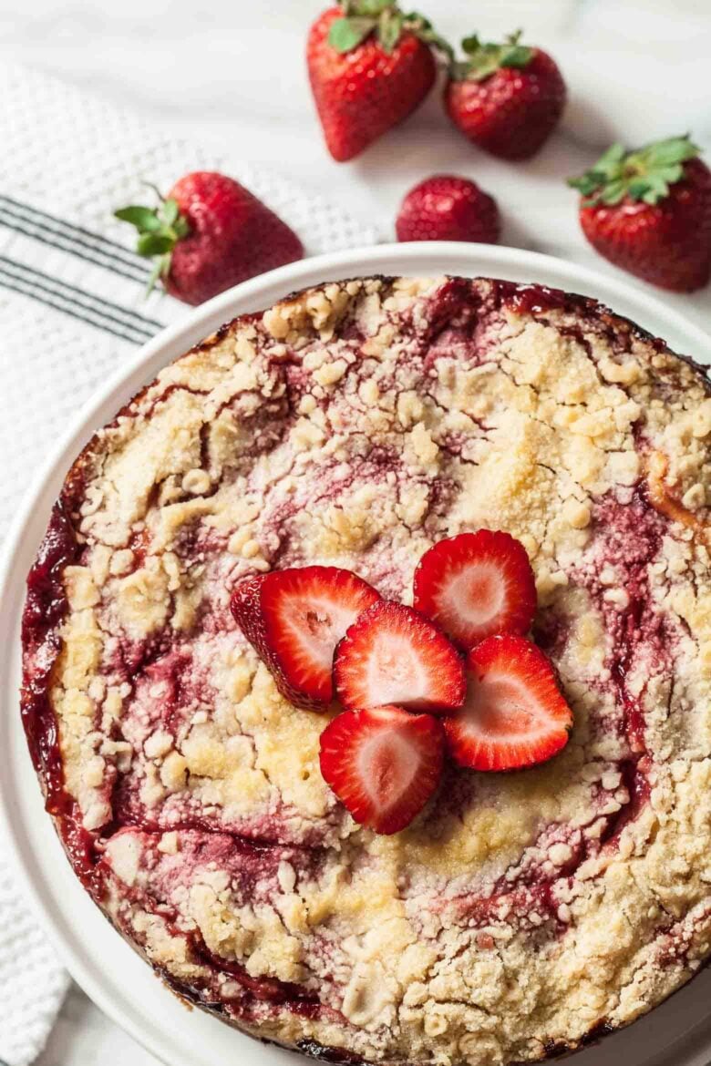 A freshly baked strawberry crumb cake garnished with sliced strawberries on top.
