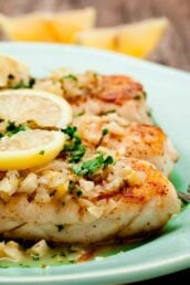white fish with lemon butter sauce plated and garnished.