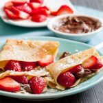 Crepes filled with Nutella and fresh strawberries, served with extra fruit and Nutella on the side.