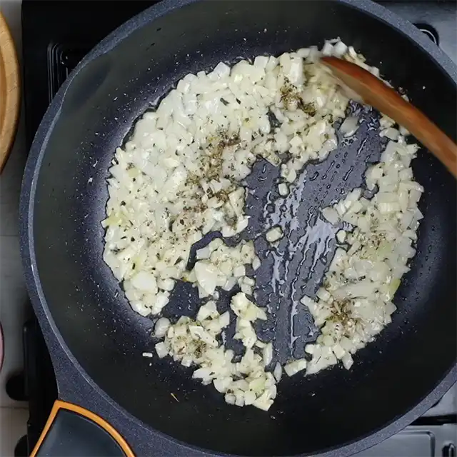 Onions and garlic being sautéed in a pan to make the best meatloaf recipe.