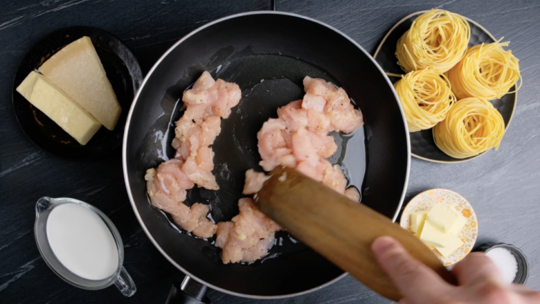 Seasoned chicken cubes being sautéed in a large skillet.